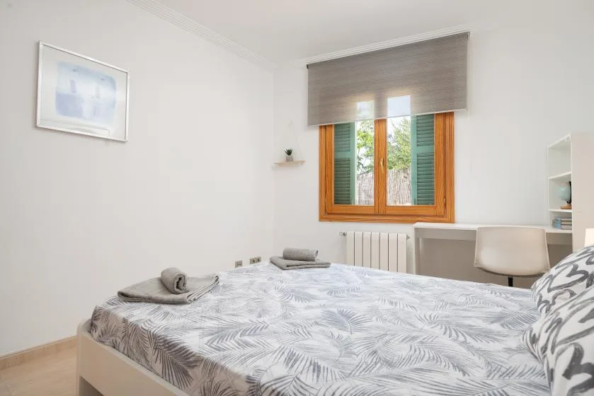 Un dormitorio con una cama debajo de una ventana con marco de madera.