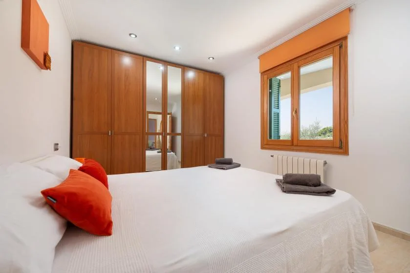 Un dormitorio con una cama grande, armarios de madera y una ventana.