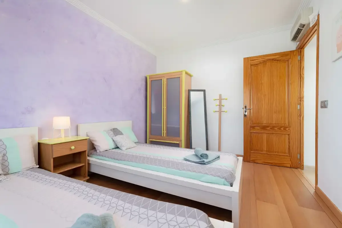 Un dormitorio con dos camas, un armario y una puerta de madera.
