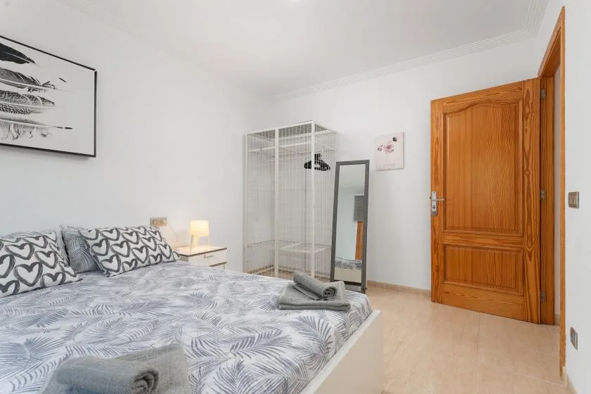 Un dormitorio con ropa de cama estampada, una mesita de noche y una puerta de madera.