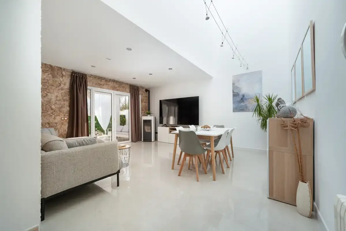 Una luminosa sala de estar y comedor con sofá, mesa y televisor.