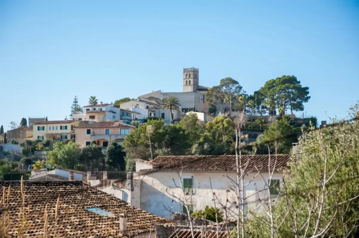 Un pueblo en una ladera con edificios agrupados y una destacada torre de piedra.