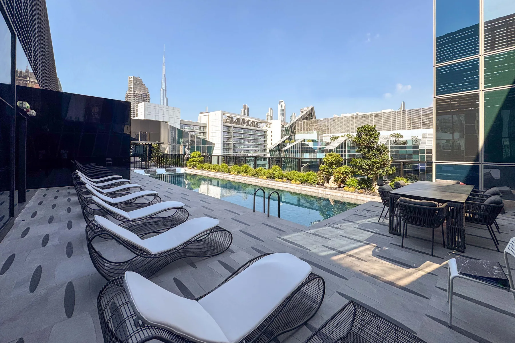 Una terraza en la azotea con piscina, tumbonas y una mesa de comedor.