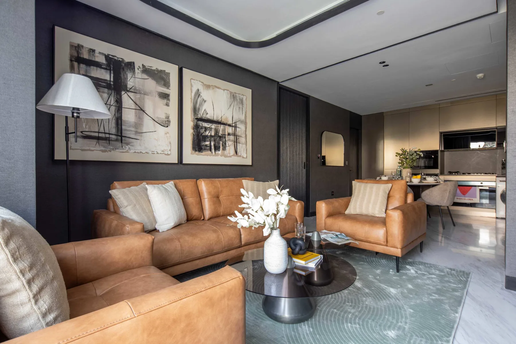 A modern living room with leather seating and a small open kitchen.