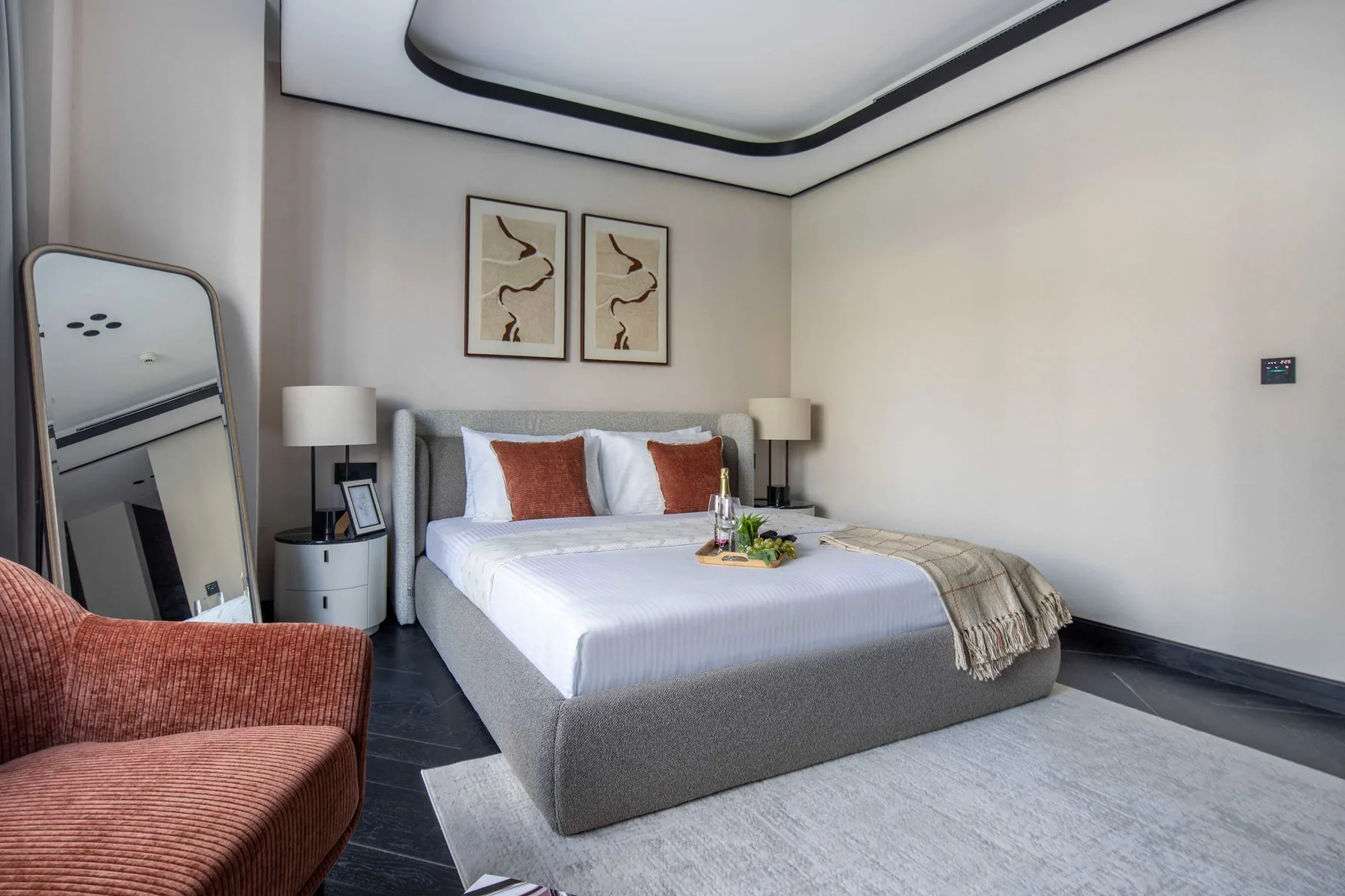 Un dormitorio con una cama bien arreglada y cuadros enmarcados encima.