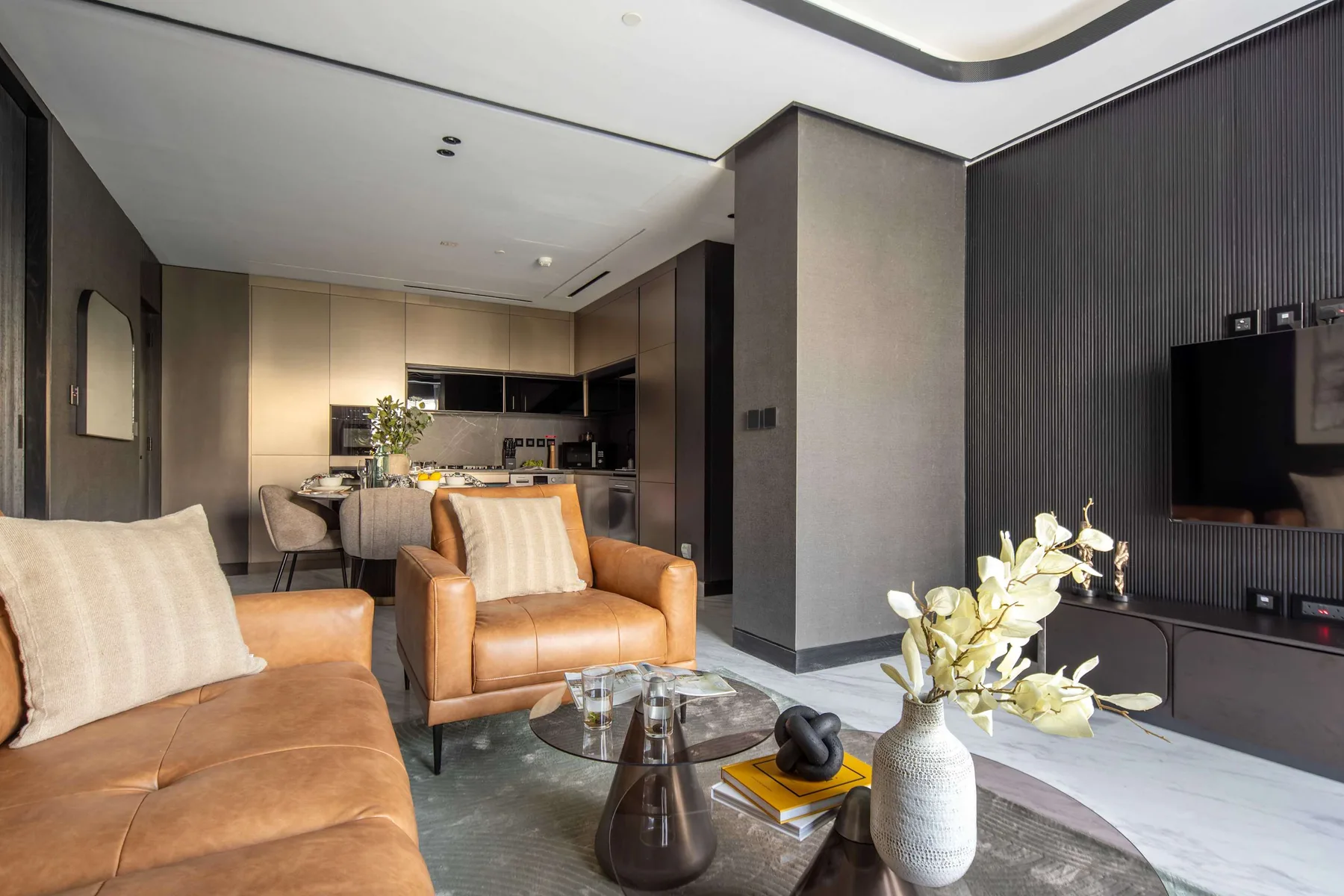 A modern living room with leather seating, a coffee table, and an open kitchen.