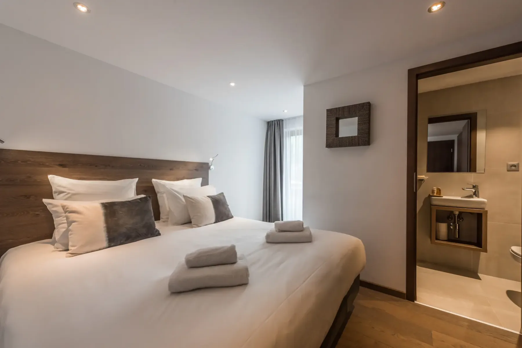 Un dormitorio con una cama grande, toallas dobladas y una vista al baño.