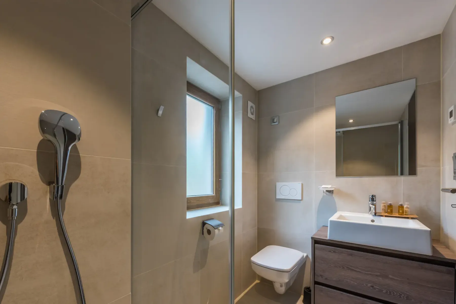 Un baño revestido de azulejos con ducha, inodoro y lavabo.