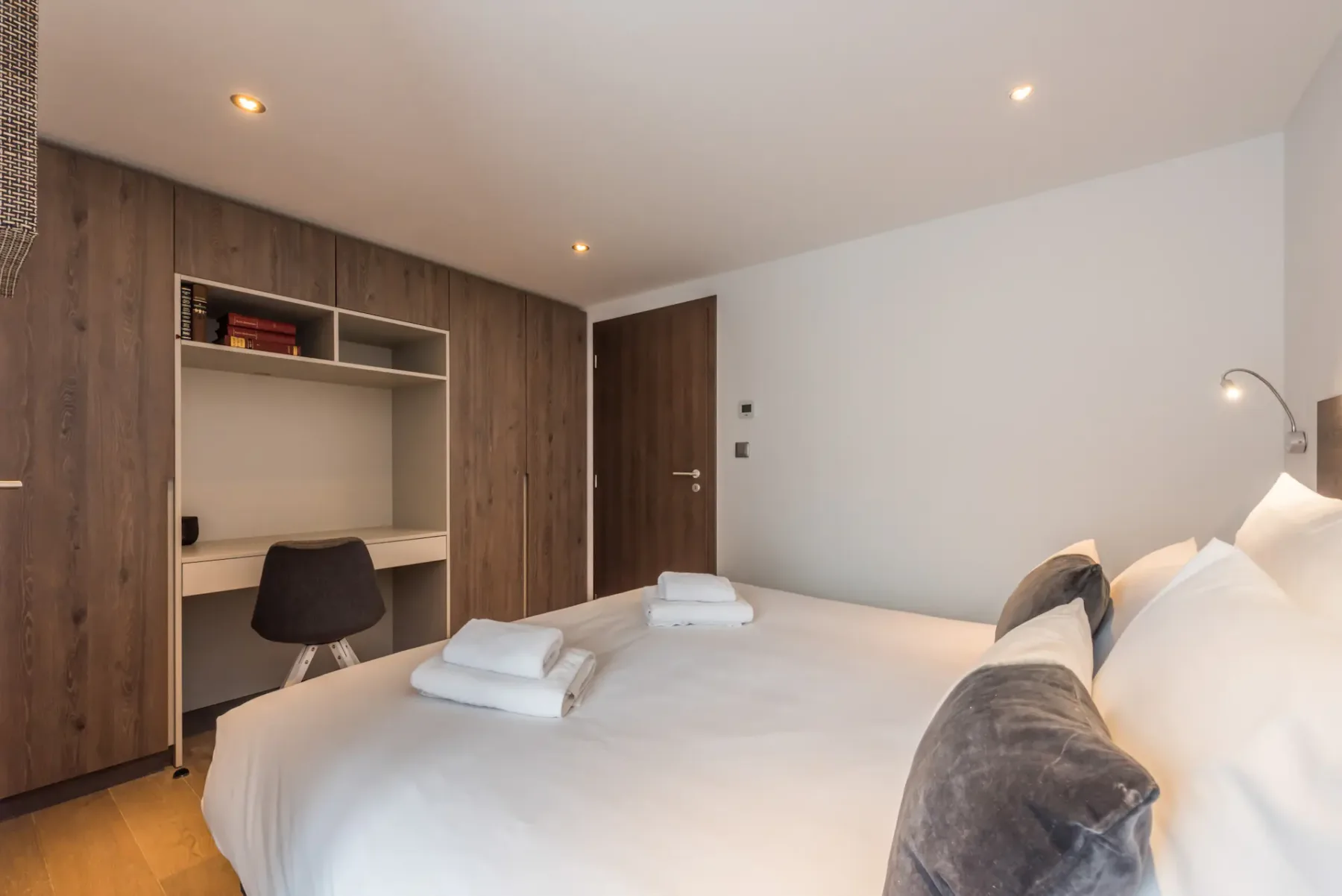 Un dormitorio con una cama grande, estantes empotrados y una puerta de madera.