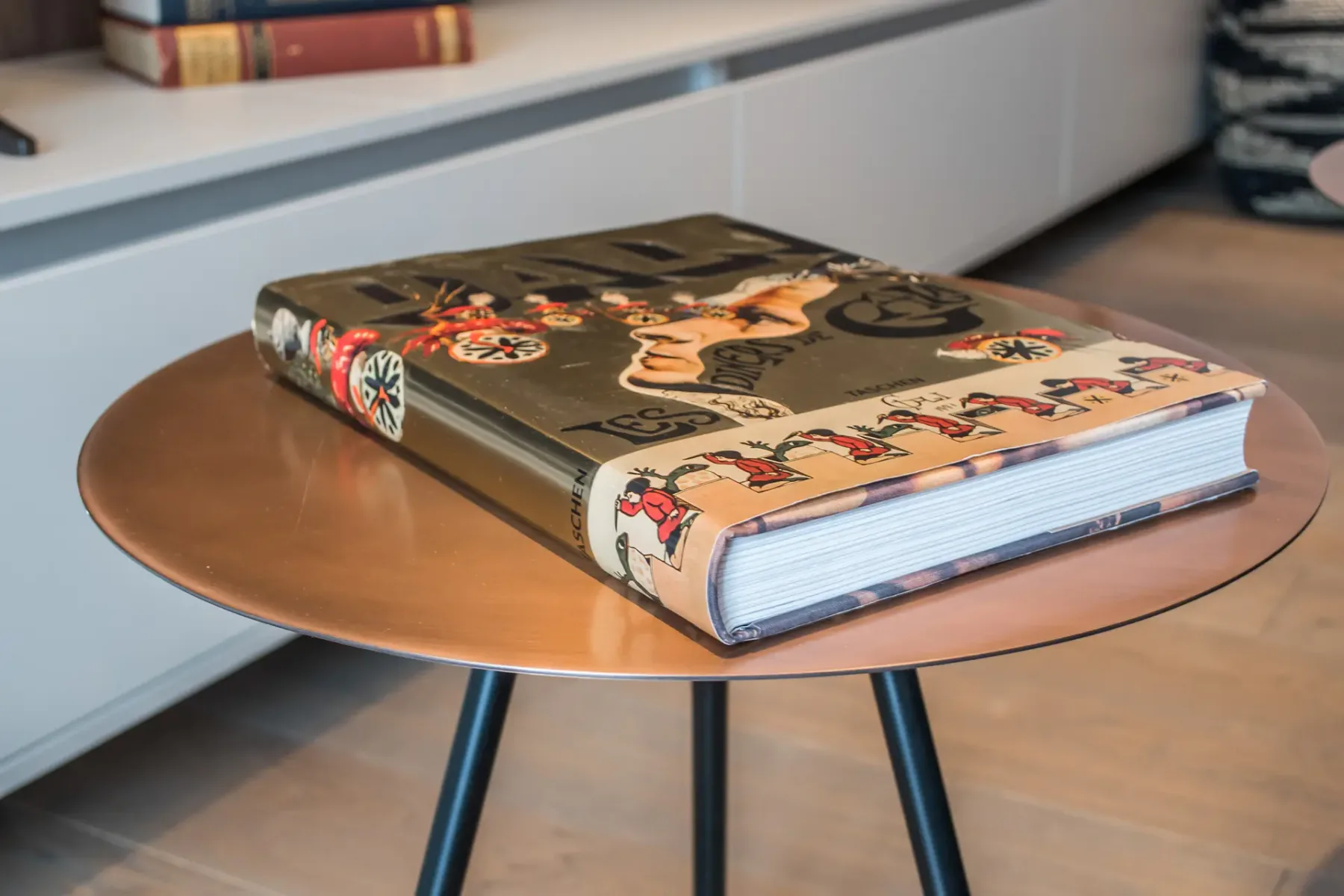 Un libro ilustrado está sobre una mesa redonda en una sala de estar.