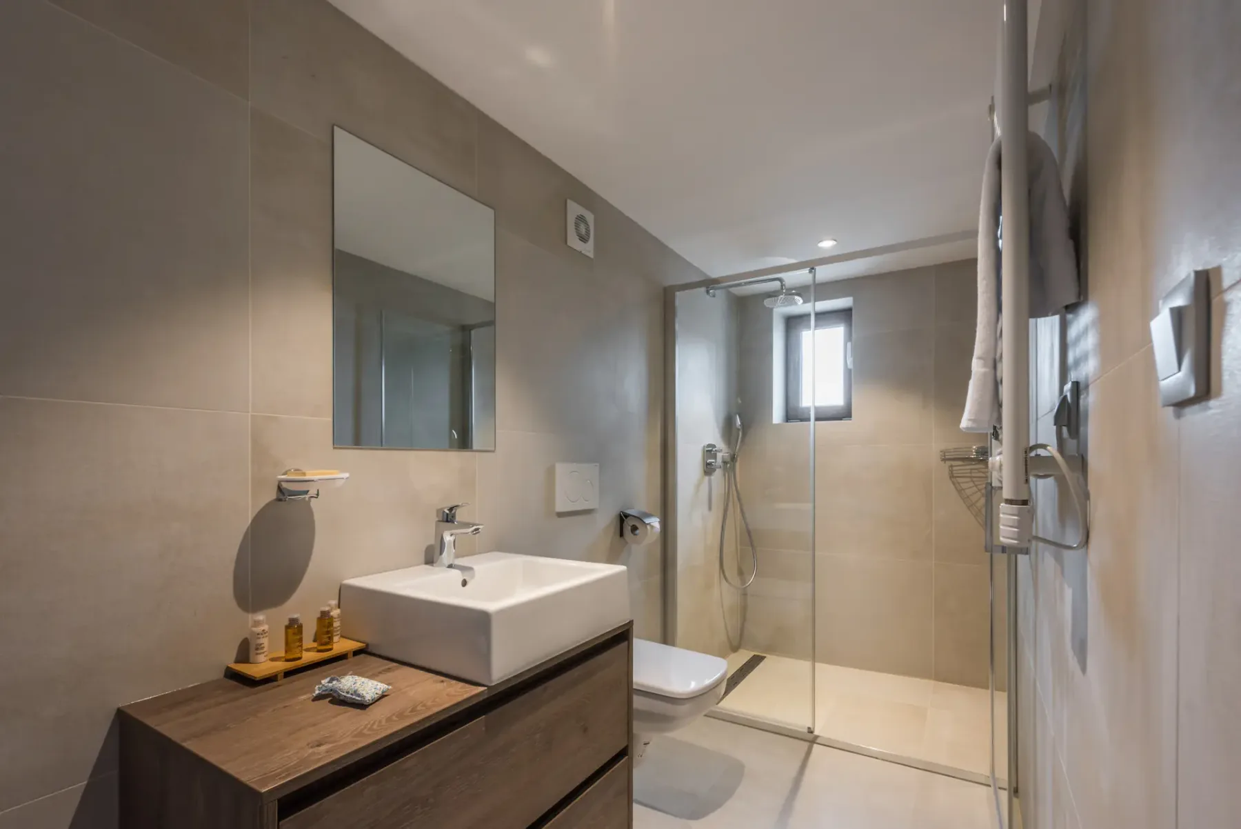 Un baño moderno con lavabo y ducha tras paneles de vidrio.