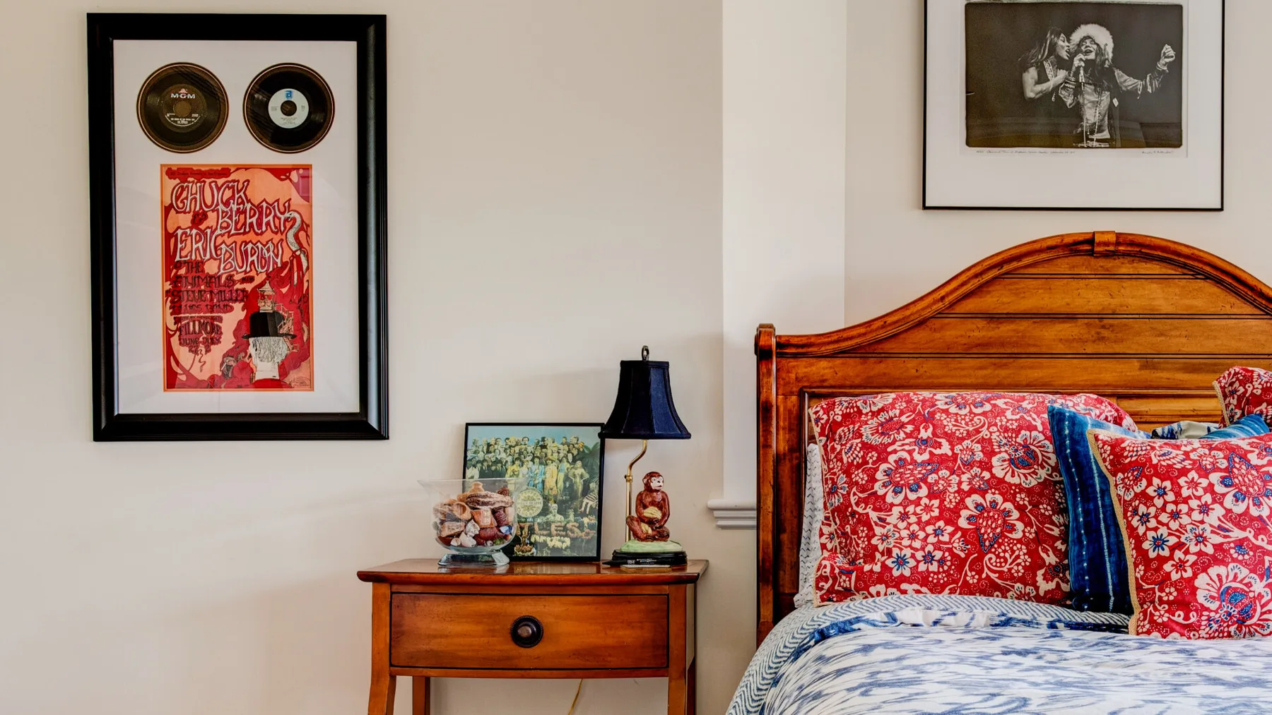 Un dormitorio con una cama de madera, almohadas coloridas y cuadros enmarcados.