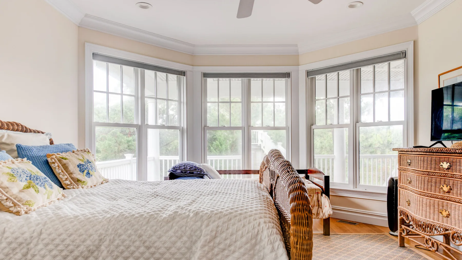 Un dormitorio luminoso con una cama junto a grandes ventanas y una cómoda.