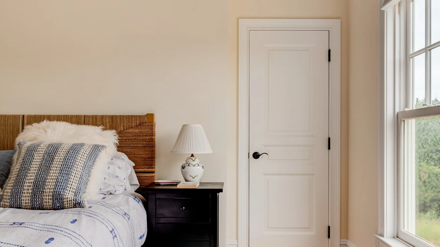Un dormitorio con una cama junto a una mesita de noche y una ventana.