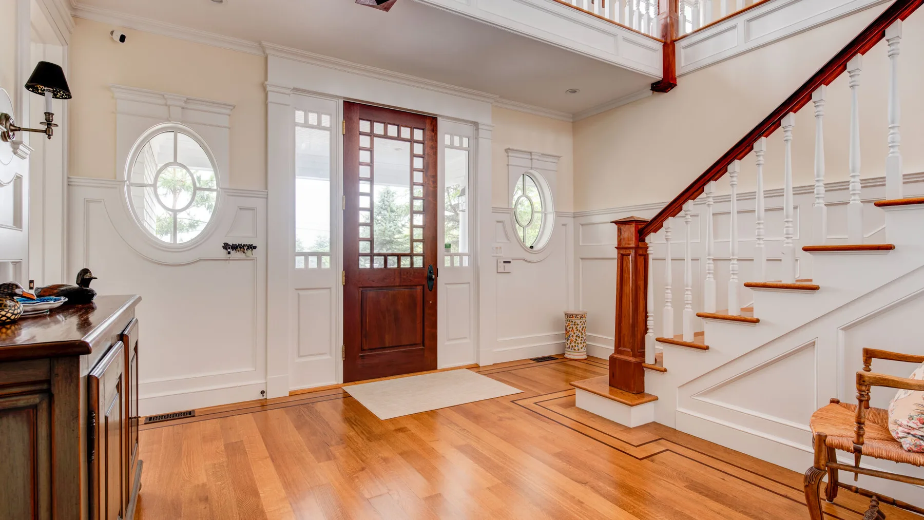 Un recibidor luminoso con una puerta principal de madera y una escalera.