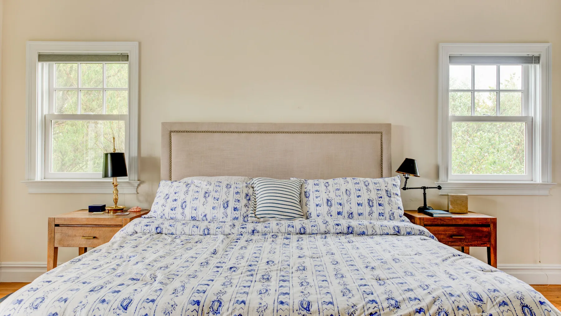 Un dormitorio con una cama grande vestida con ropa de cama estampada en azul y blanco.