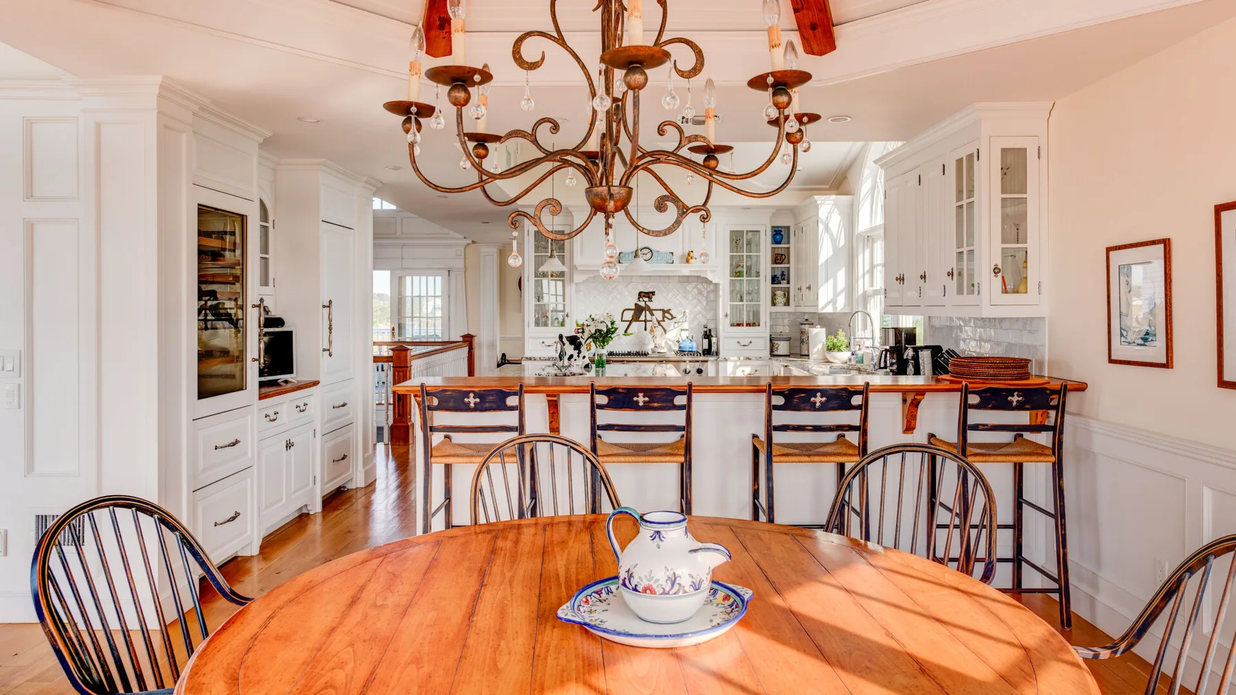 Una cocina y comedor luminosos con una mesa redonda de madera y asientos en la isla.