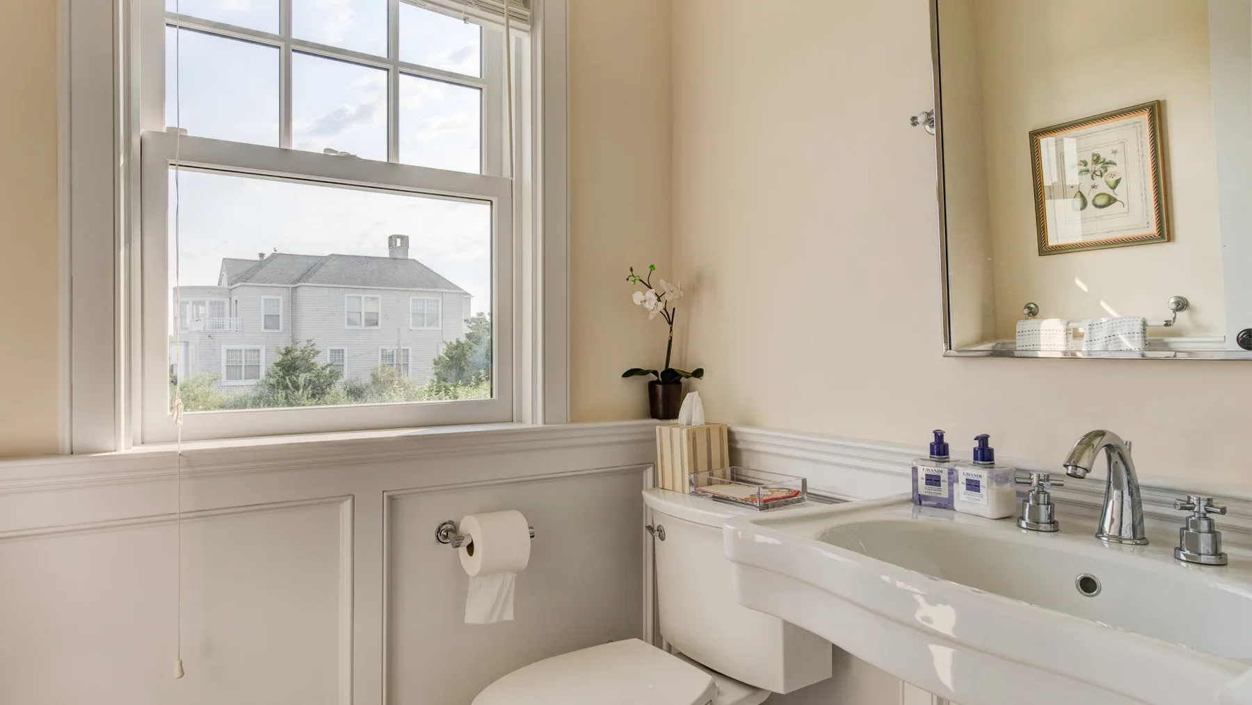 Un baño luminoso con un lavabo amplio bajo una ventana grande.