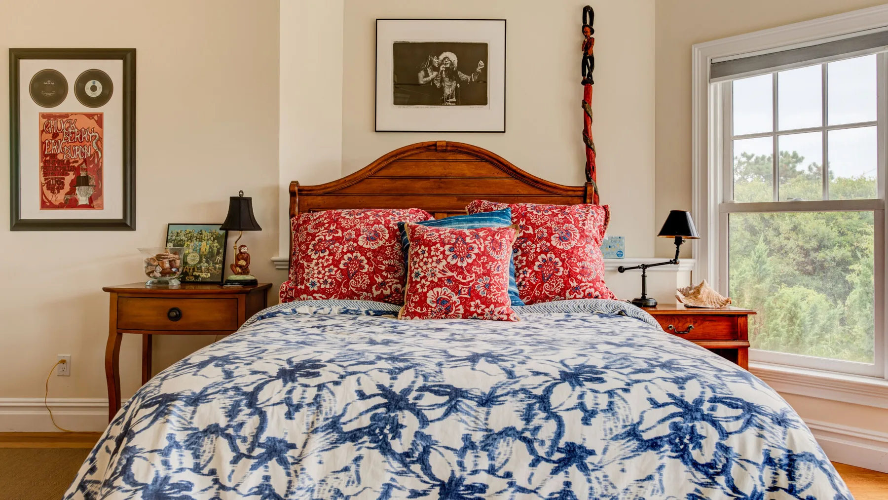 Dormitorio con una cama de madera vestida con ropa de cama floral azul y blanca.