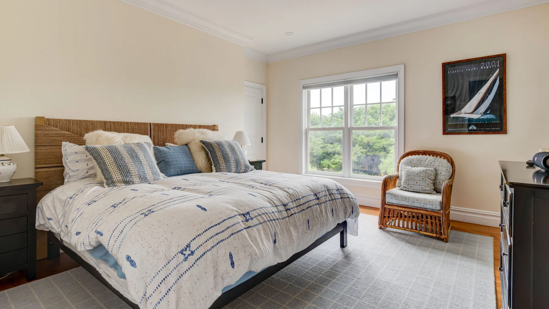 Un dormitorio con una cama grande, una ventana y una silla de mimbre.