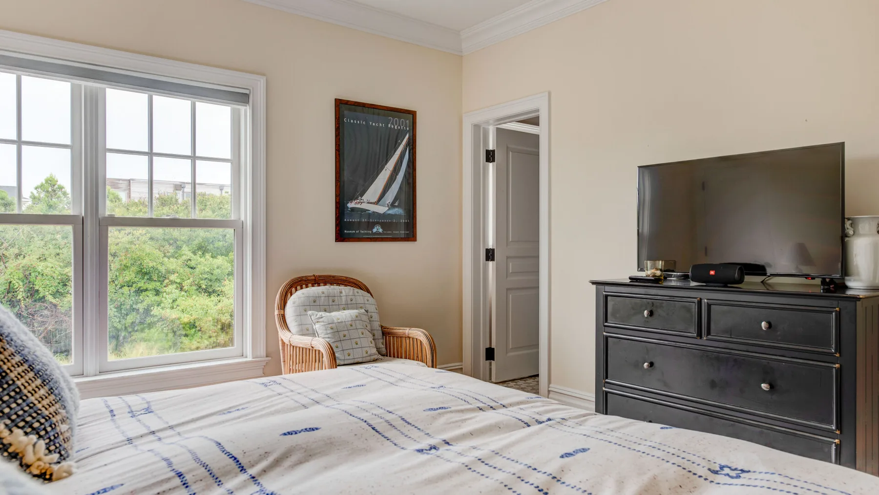 Un dormitorio con una cama, una ventana y un televisor sobre una cómoda.