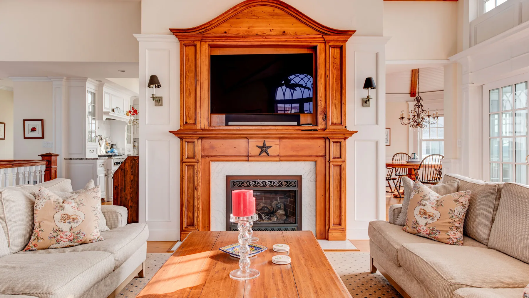 Una sala de estar luminosa con asientos alrededor de una chimenea de madera y un televisor.