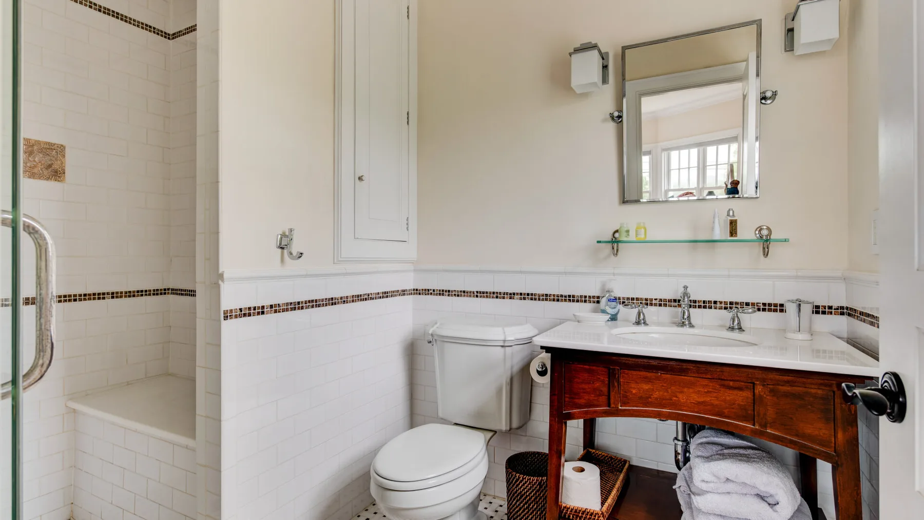 Un baño con azulejos, inodoro, lavabo y espejo.