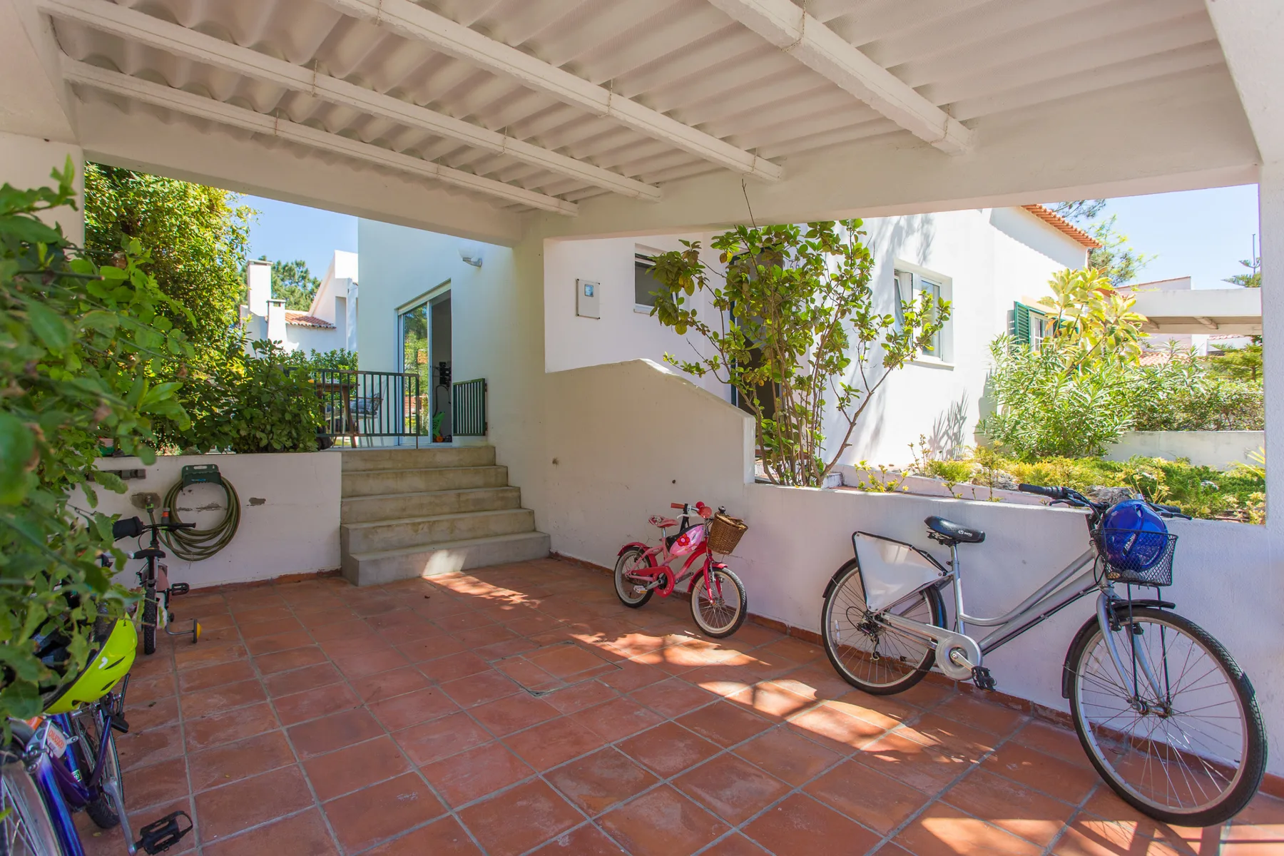 Un patio exterior cubierto con bicicletas junto a unos escalones y plantas.