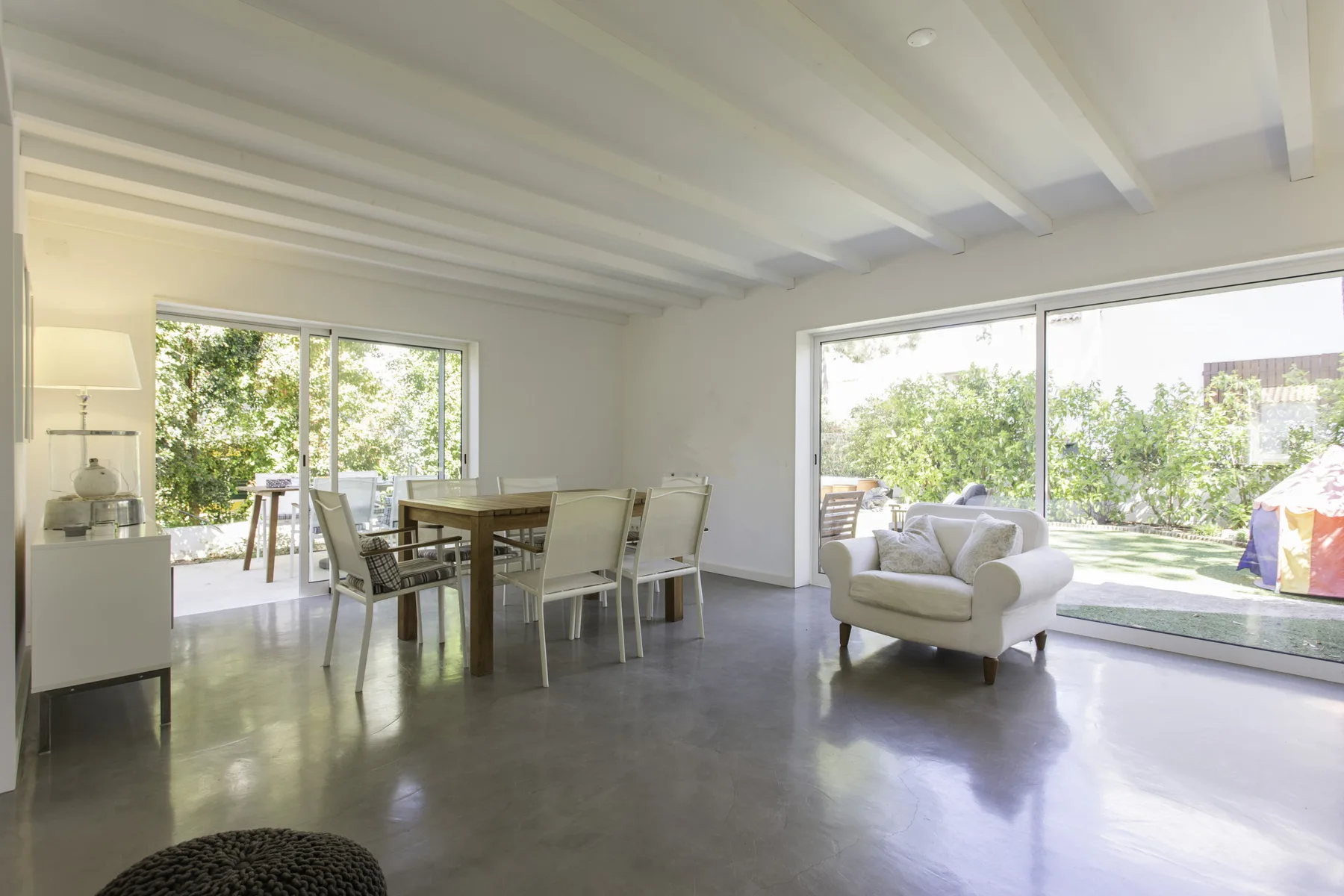 Un comedor y sala de estar luminosos se abren al jardín mediante grandes puertas de vidrio.