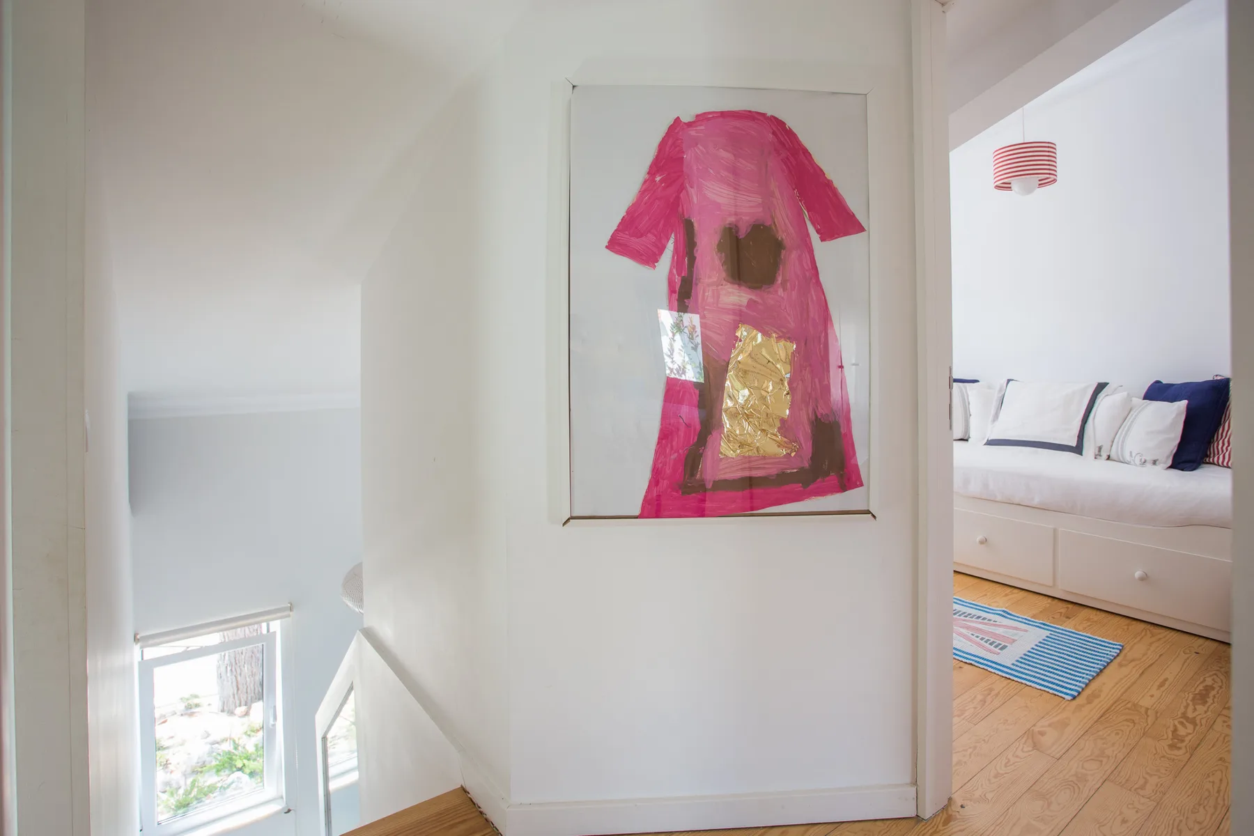 Un pasillo muestra una obra colorida junto a un dormitorio contiguo.
