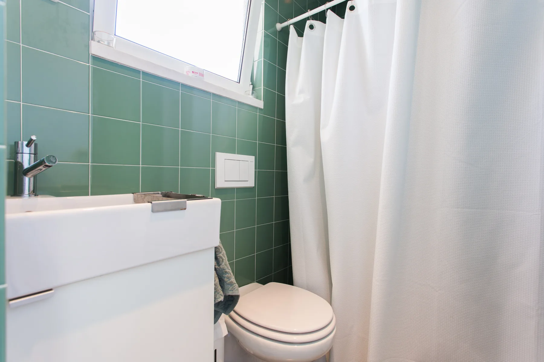 Un baño con lavabo, inodoro y cortina de ducha blanca.