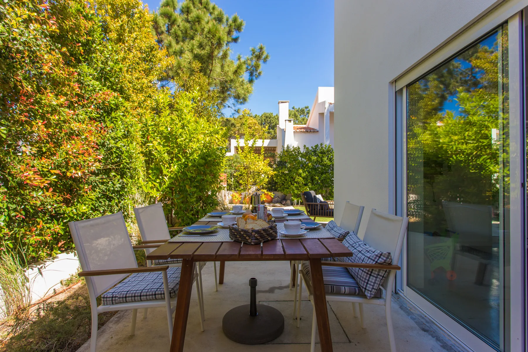 Comedor al aire libre con una mesa larga y asientos junto a una puerta de vidrio.
