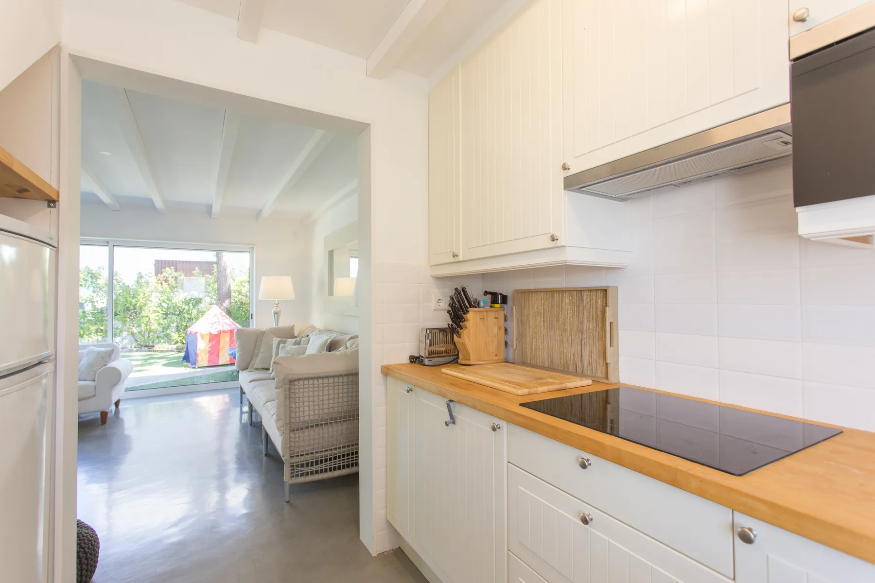 Una cocina luminosa con encimera de madera se abre a una sala de estar.