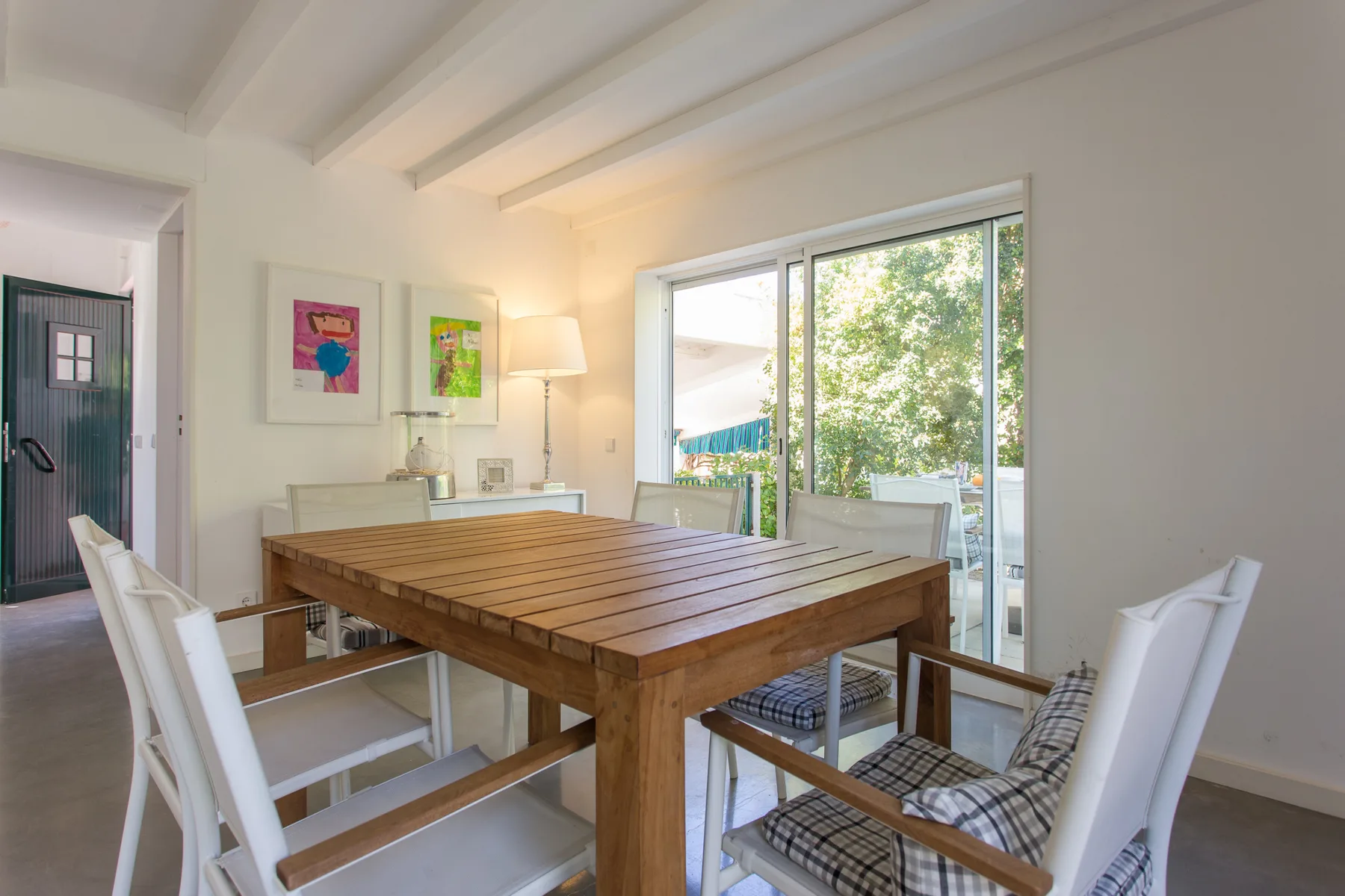 Comedor con una mesa de madera y sillas junto a grandes ventanales.