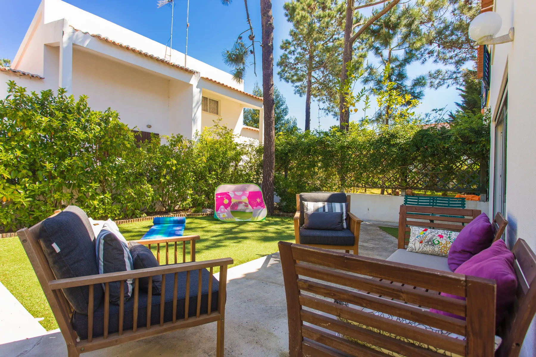 Una zona de estar al aire libre con muebles de madera y un pequeño césped.