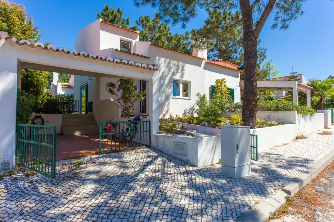 Una casa blanca con entrada cubierta y patio pavimentado.