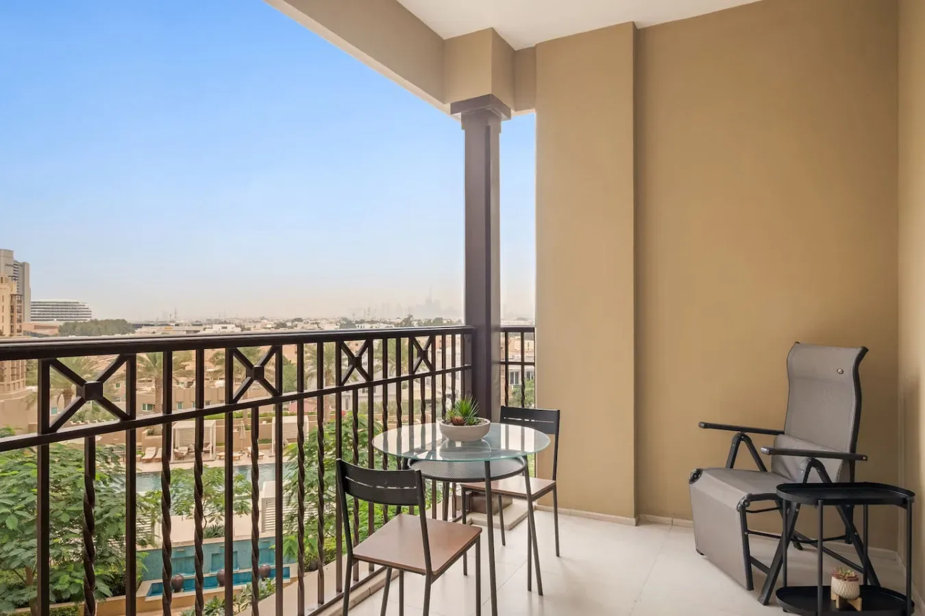 A balcony seating area overlooks nearby buildings and greenery.