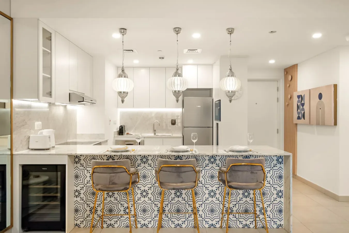 A bright kitchen with a patterned island and pendant lights.