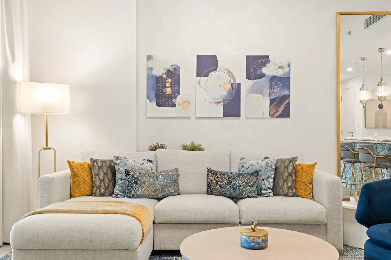 A bright living room features a light-colored sofa beneath abstract wall art.