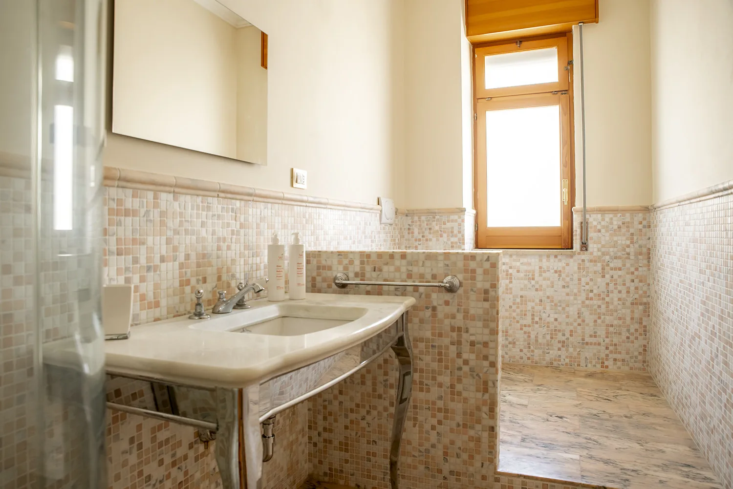 Un baño con azulejos, un lavabo amplio y una ventana.