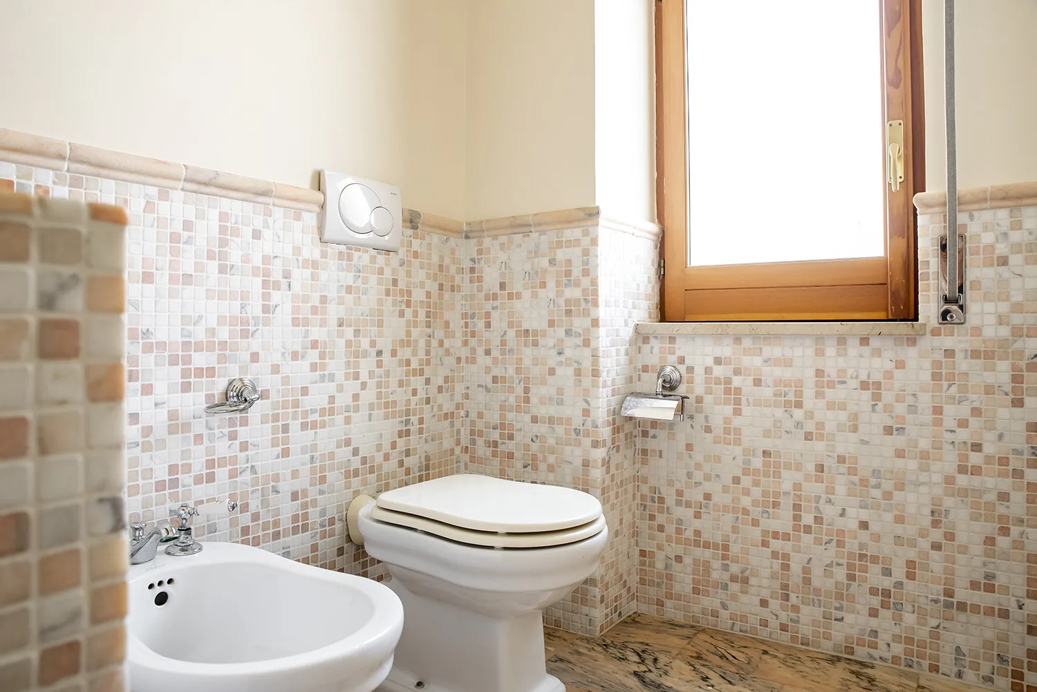 Un baño con azulejos, inodoro, lavabo y ventana.
