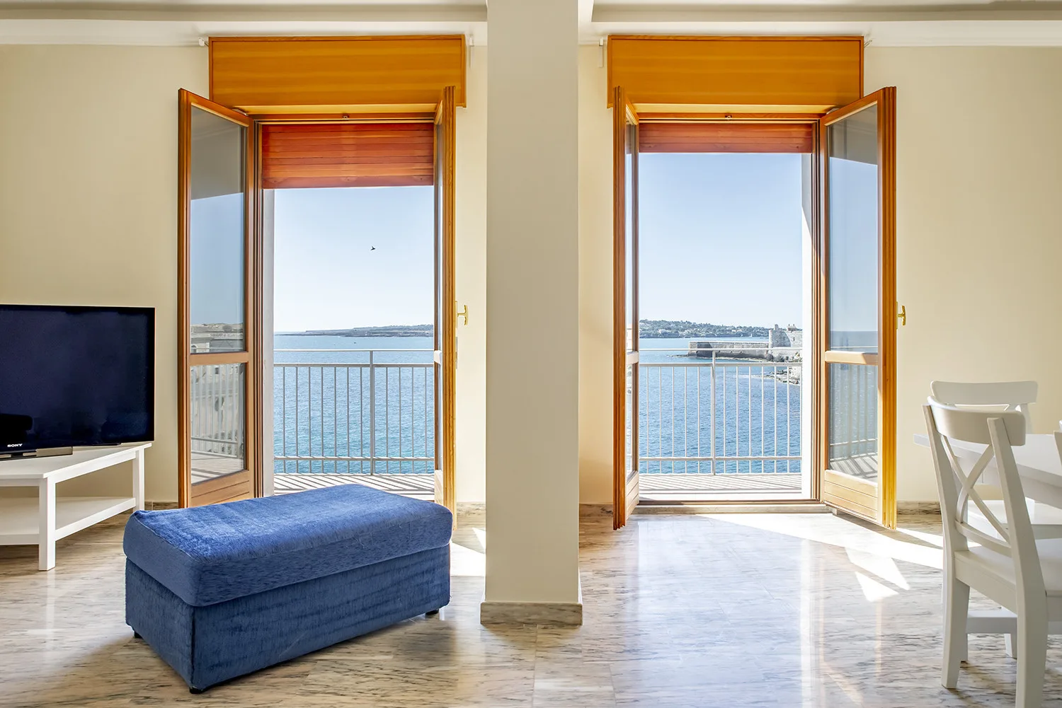 Una luminosa sala de estar da a un balcón con vistas al agua.