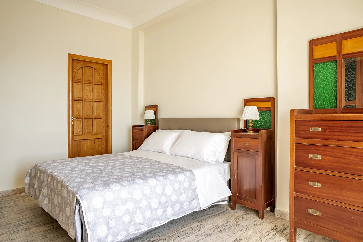 Un dormitorio con una cama doble, mesitas de noche y una cómoda de madera.