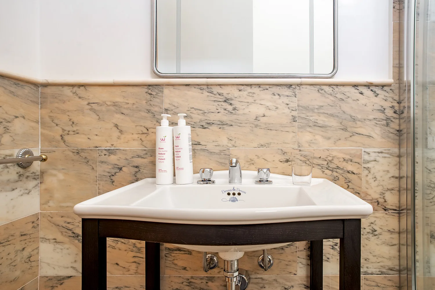 Un lavabo de baño con una pileta blanca, un espejo y azulejos con vetas.