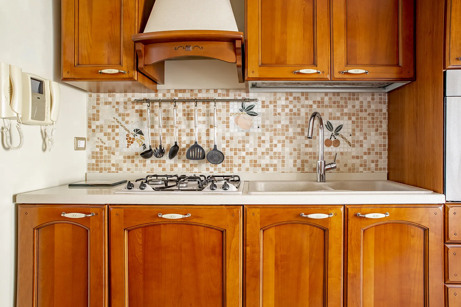 Una cocina con gabinetes de madera, una estufa y un salpicadero de azulejos.