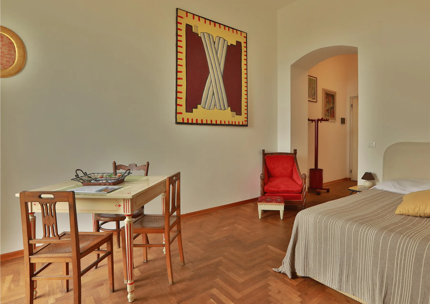 A bedroom with a bed, a small table, and a red armchair.