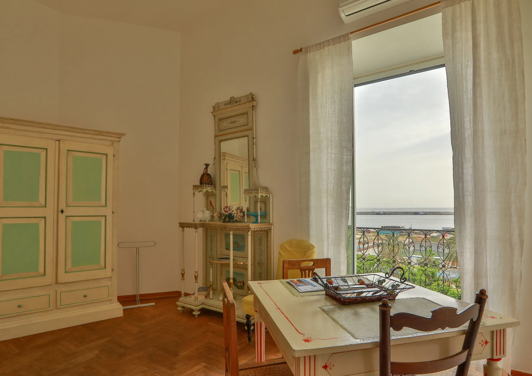 A dining area with a table and chairs beside a large window overlooking the water.