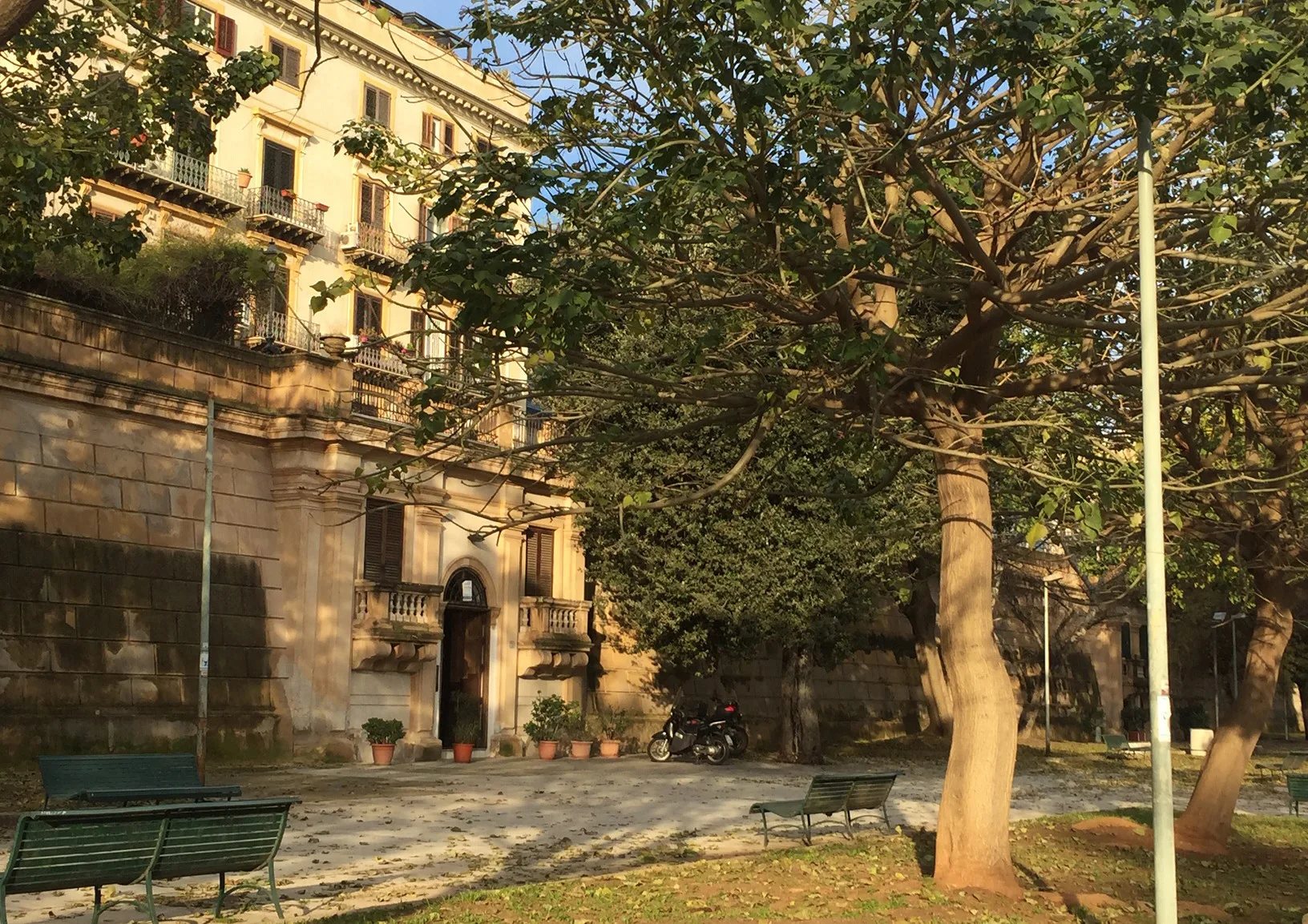A leafy courtyard in front of a pale multi-story building.