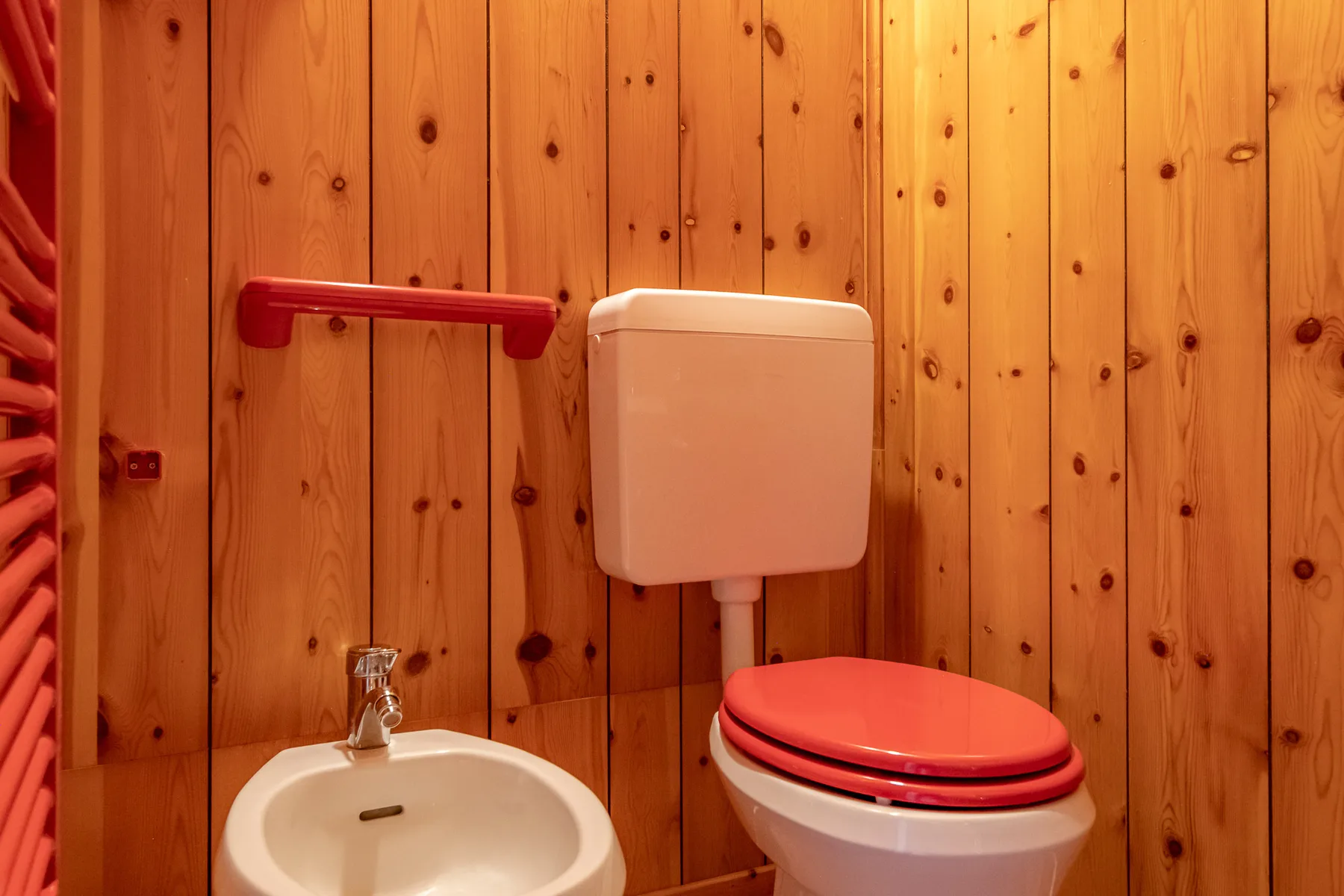 Un baño compacto con lavabo e inodoro junto a paredes revestidas de madera.
