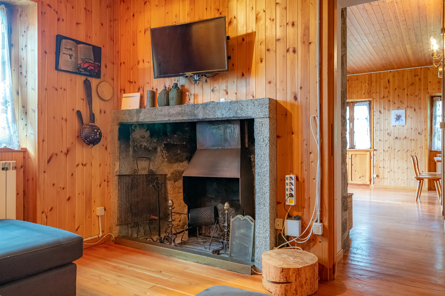 A wood-paneled living room centers on a stone fireplace, with a television mounted above it.